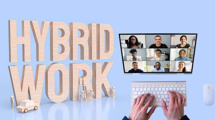 lustracija hibridnog modela rada sa velikim natpisom “Hybrid Work”, video-pozivom na ekranu i rukama koje kucaju na tastaturi.
